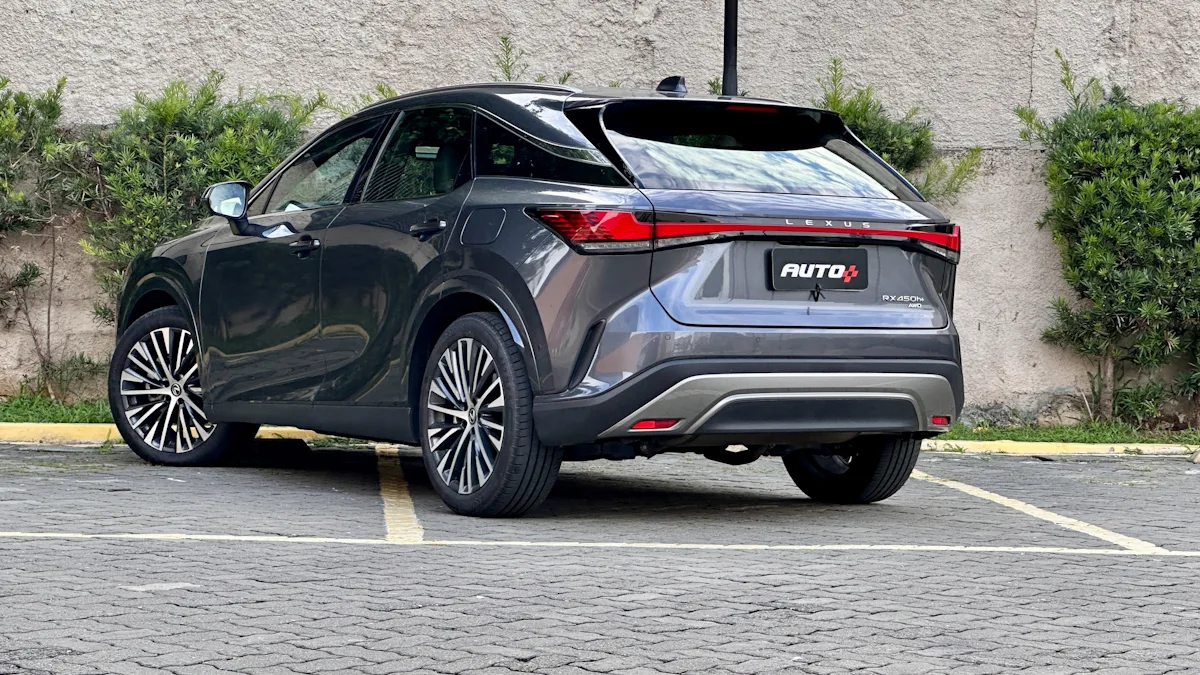 Lexus RX450h cinza de traseira em um estacionamento com um muro de plantas atrás