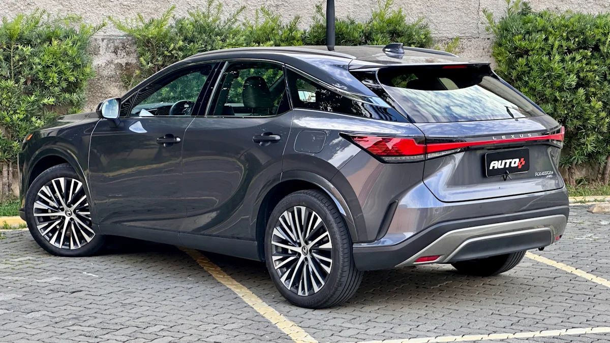 Lexus RX450h cinza de traseira em um estacionamento com um muro de plantas atrás