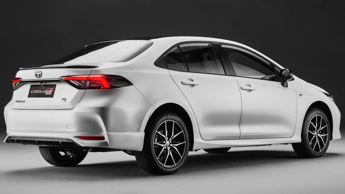 Toyota Corolla GR-Sport 2025 branco, visto de trás, com lanternas ligadas e fundo escuro