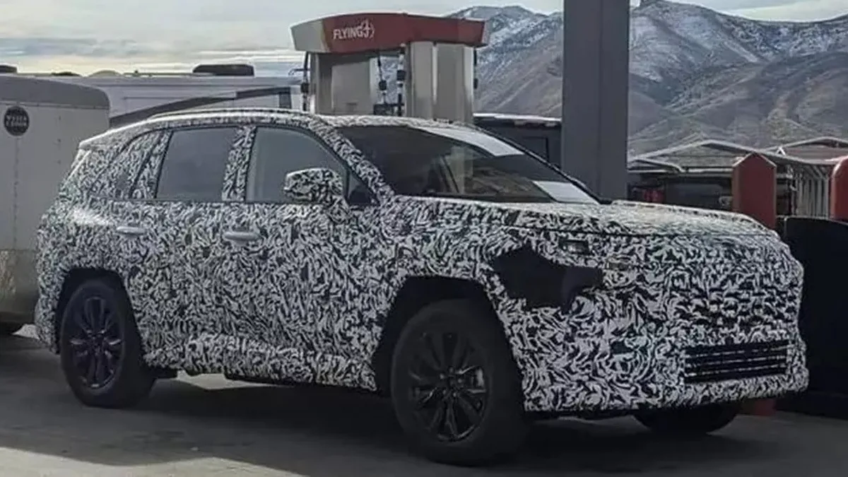 Novo Toyota RAV4 sob forte camuflagem parado de lateral no posto de combustível