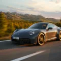 Porsche 911 Carrera GTS T-Hybrid cinza andando na estrada com montanhas ao fundo