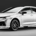 Novo Toyota Corolla GR-Sport 2025 branco, visto de frente e com fundo escuro