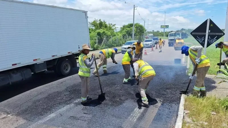 Homens trabalhando na instalação da faixa elevada na SC-401 com caminhão passando