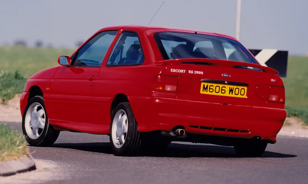 Ford Escort sapão na cor vermelha de traseira fazendo uma curva forte