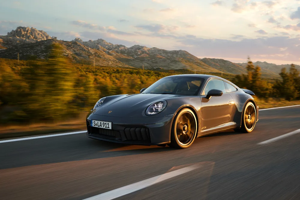 Porsche 911 Carrera GTS T-Hybrid cinza andando na estrada com montanhas ao fundo