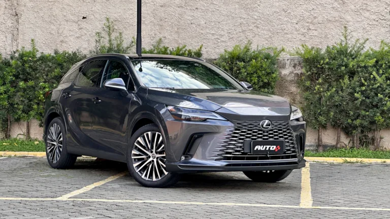 Lexus RX450h cinza de frente em um estacionamento com um muro de plantas atrás