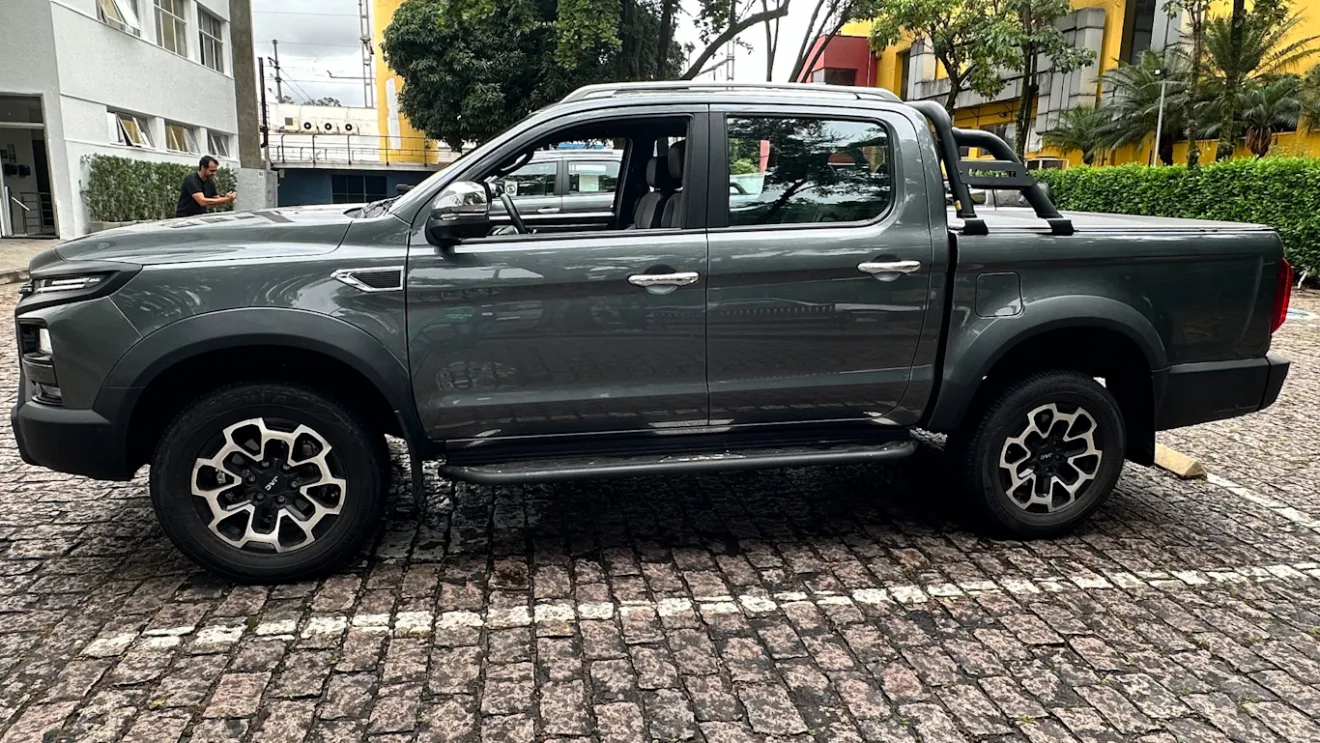 JAC Hunter cinza, vista de lado, com árvore ao fundo e vidros abertos