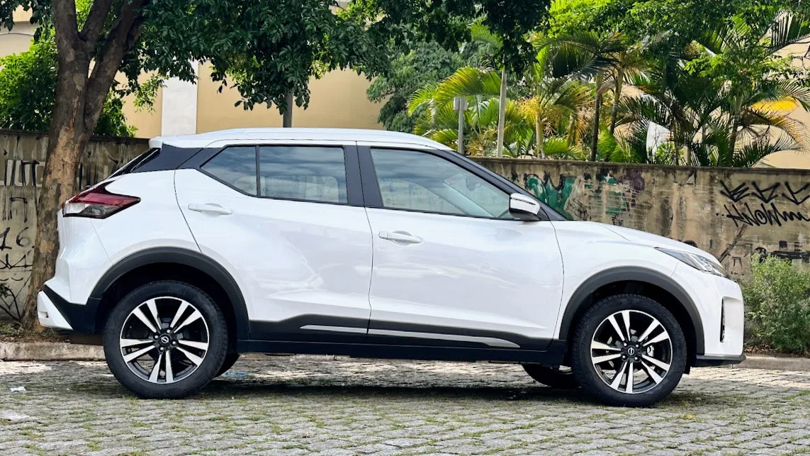 Nissan Kicks branco parado de lateral com muro ao fundo