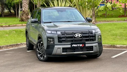 Hyundai Creta Ultimate cinza com teto preto estacionado mostrando a frente com um jardim ao fundo