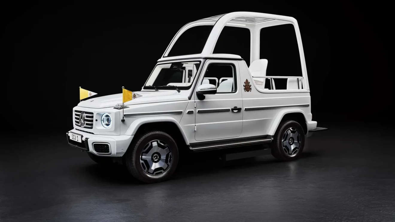 Mercedes-Benz Classe G elétrico branco como Papamóvel, com faróis acesos e bandeirinhas amarelas, visto de frente