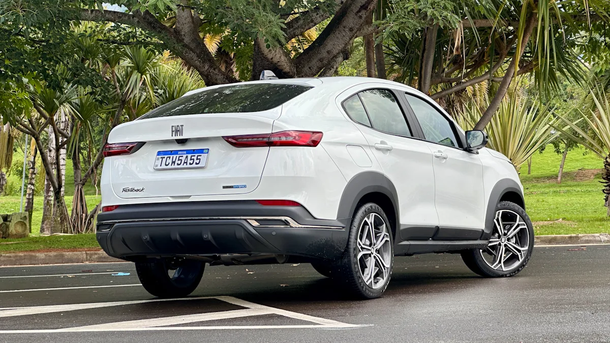 Fiat Fastback Hybrid branco de traseira em um estacionamento molhado com uma floresta ao fundo