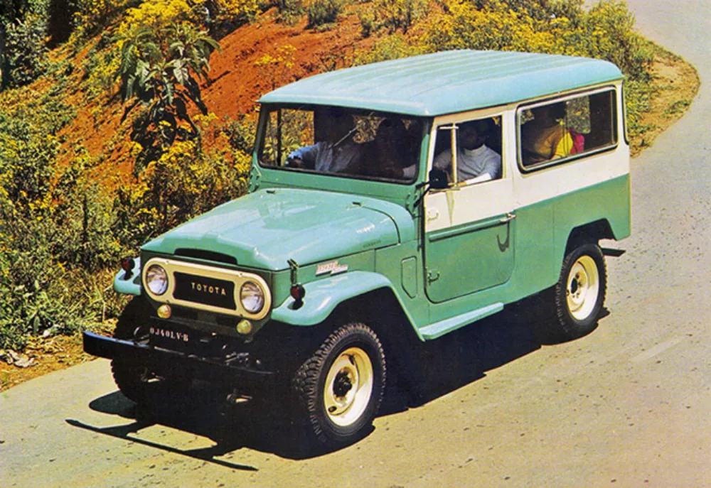 Toyota Bandeirante verde com partes brancas, visto de cima e com mato ao redor