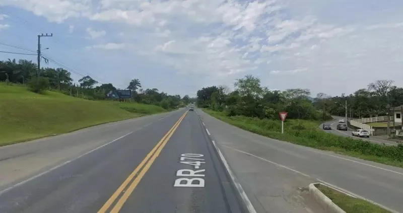 Trecho da BR-470 com mato ao redor e céu aberto