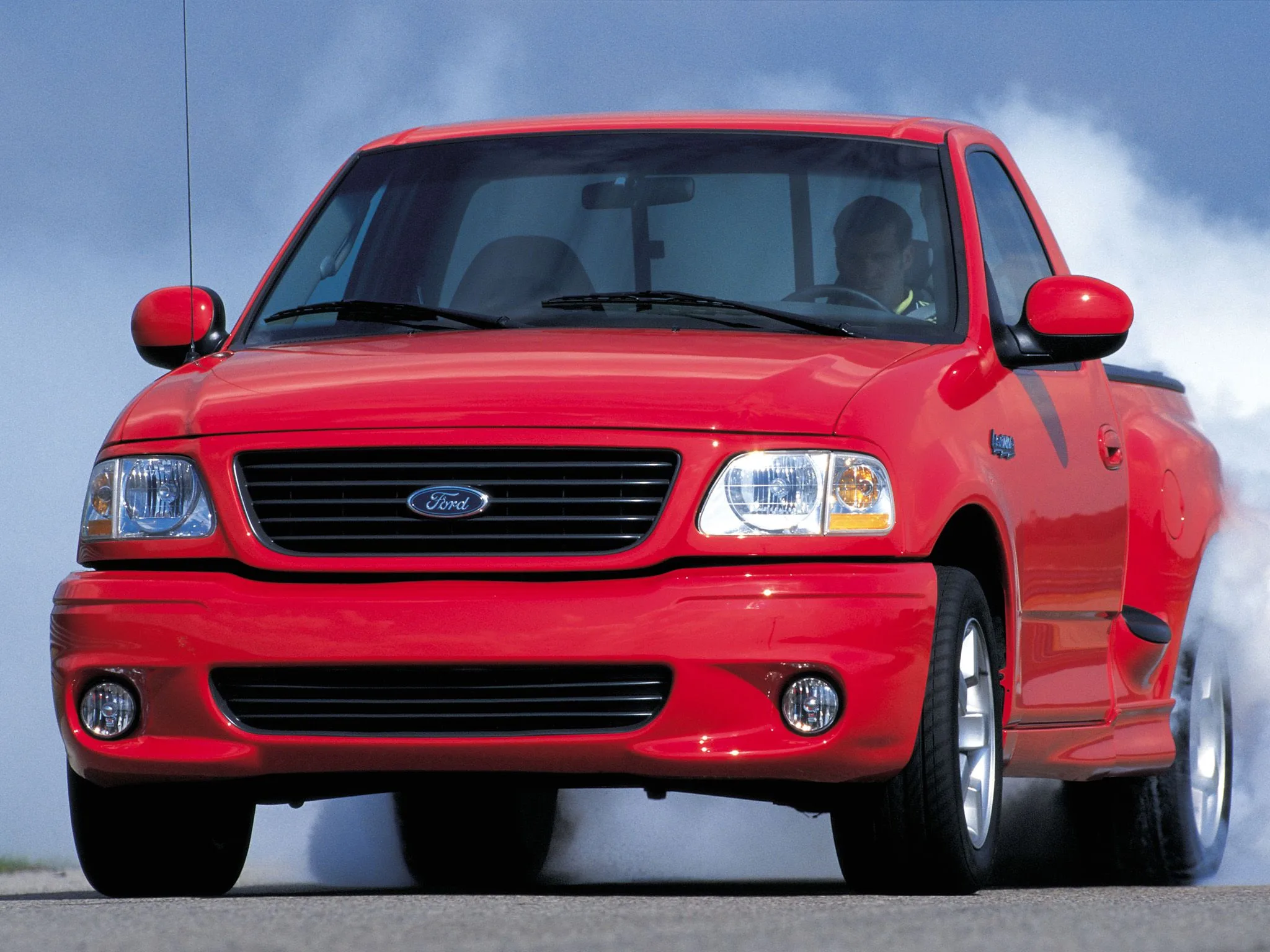 Ford SVT F-150 Lightning vermelha de frente fazendo um burn-out