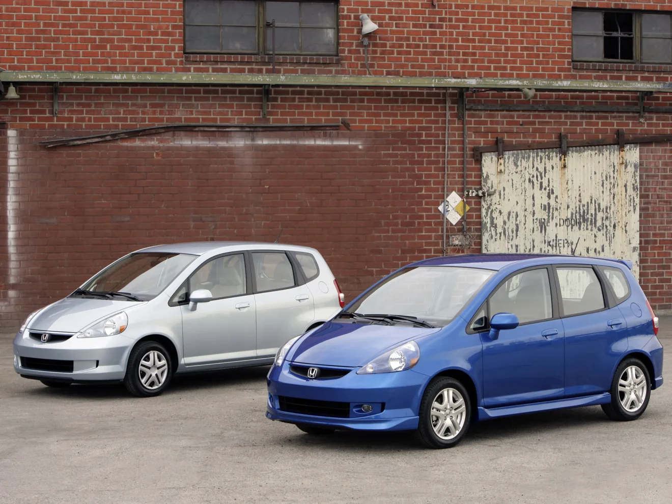 honda fit prata de primeira geração atrás de um fit azul de primeira geração