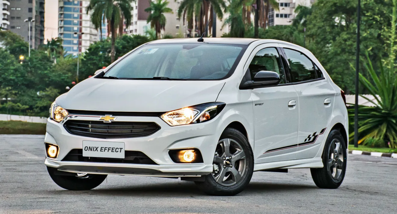 Chevrolet Onix Effect branco parado de frente com prédios e árvores ao fundo