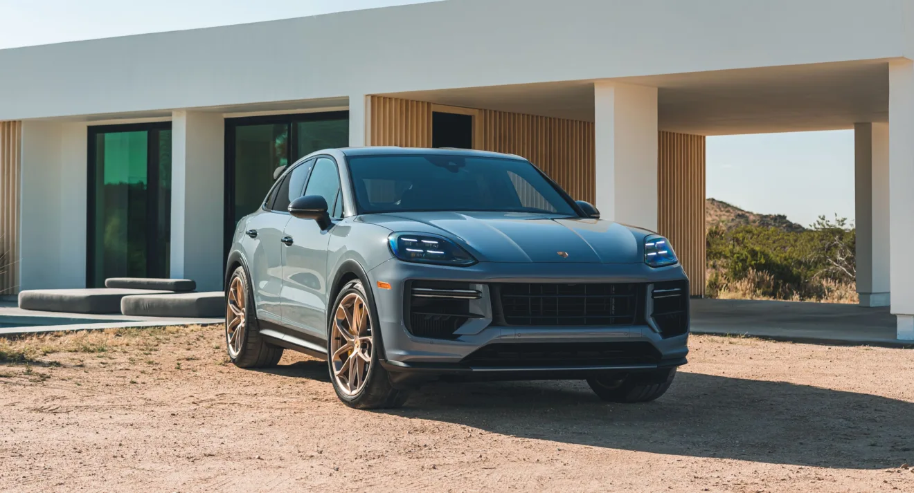 Porsche Cayenne Turbo GT cinza parado de frente com casa ao fundo