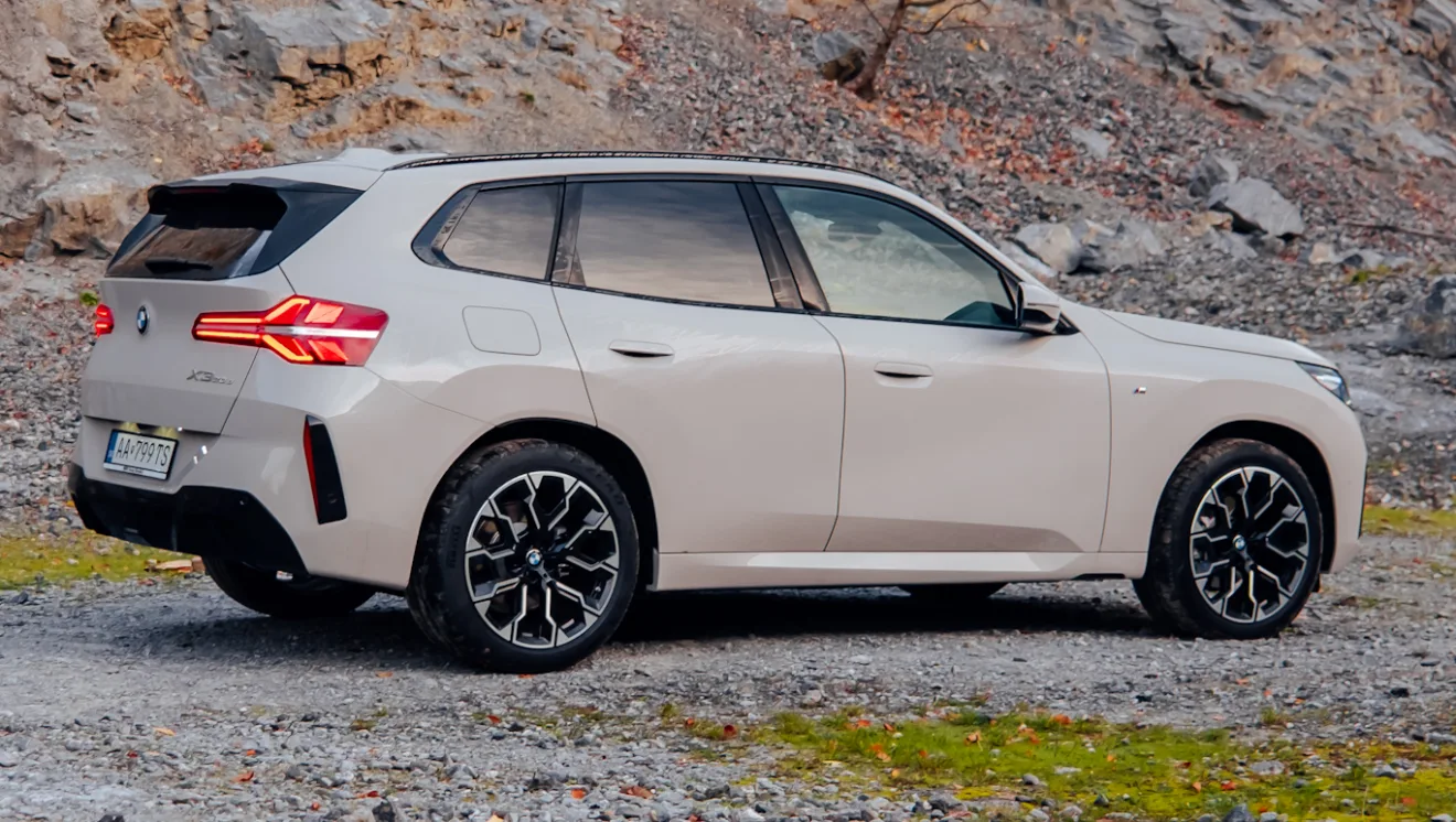 BMW X3 20d xDrive MSport branco, visto lateral mente e com lanternas acesas