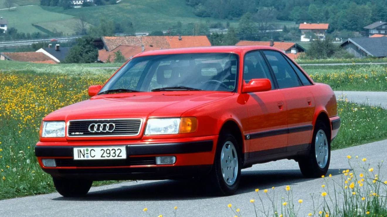 Audi 100 quattro vermelho andando na estrada com casas ao fundo