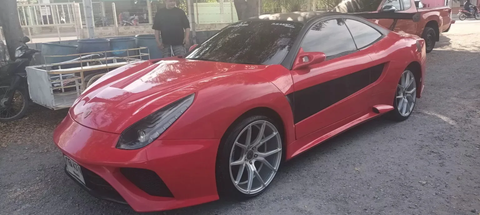 Toyota Celica que tenta ser uma réplica da Ferrari F12 Berlinetta. Vermelho, visto de lado e com pessoa ao fundo