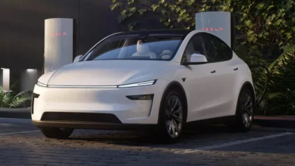 Tesla Model Y reestilizado branco, com faróis acesos, visto de frente e com fundo escuro