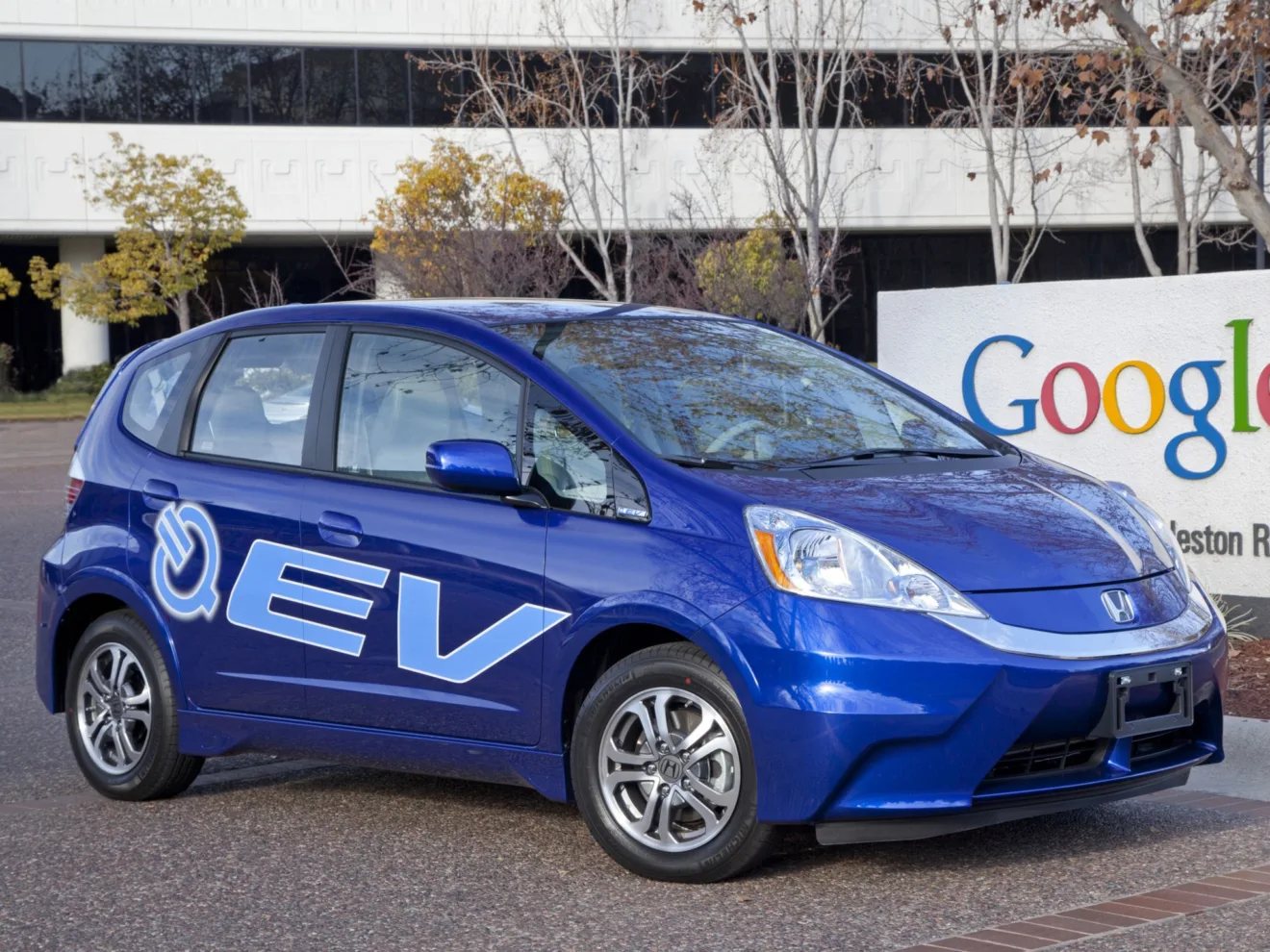 Honda Fit elétrico azul de frente a uma placa do Google