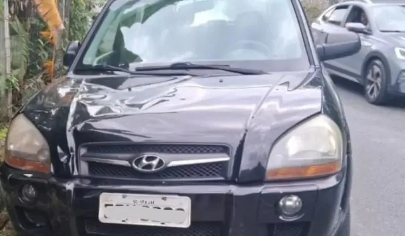 Hyundai Tucson preto, visto de frente, amassado e com placa ocultada