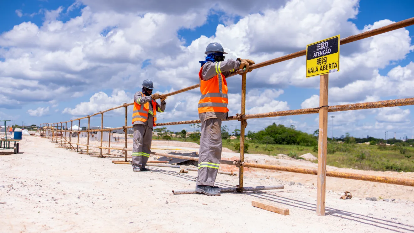 Trabalhadores realizando tarefa na planta de Camaçari, da BYD com colete laranja e capacetes cinza