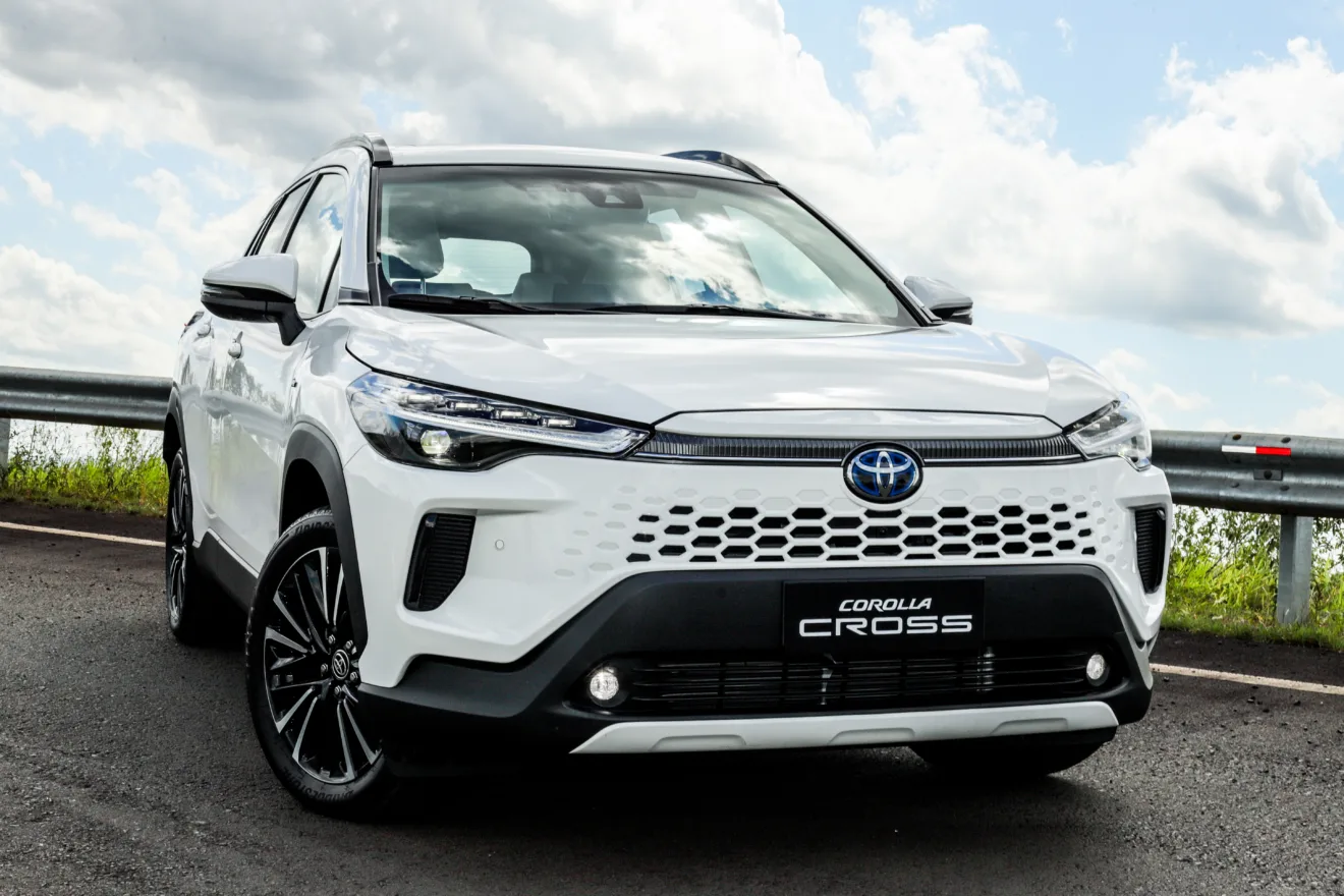 Toyota Corolla Cross 2026 branco, visto de frente com faróis, DRL's e iluminadores de neblina acesos