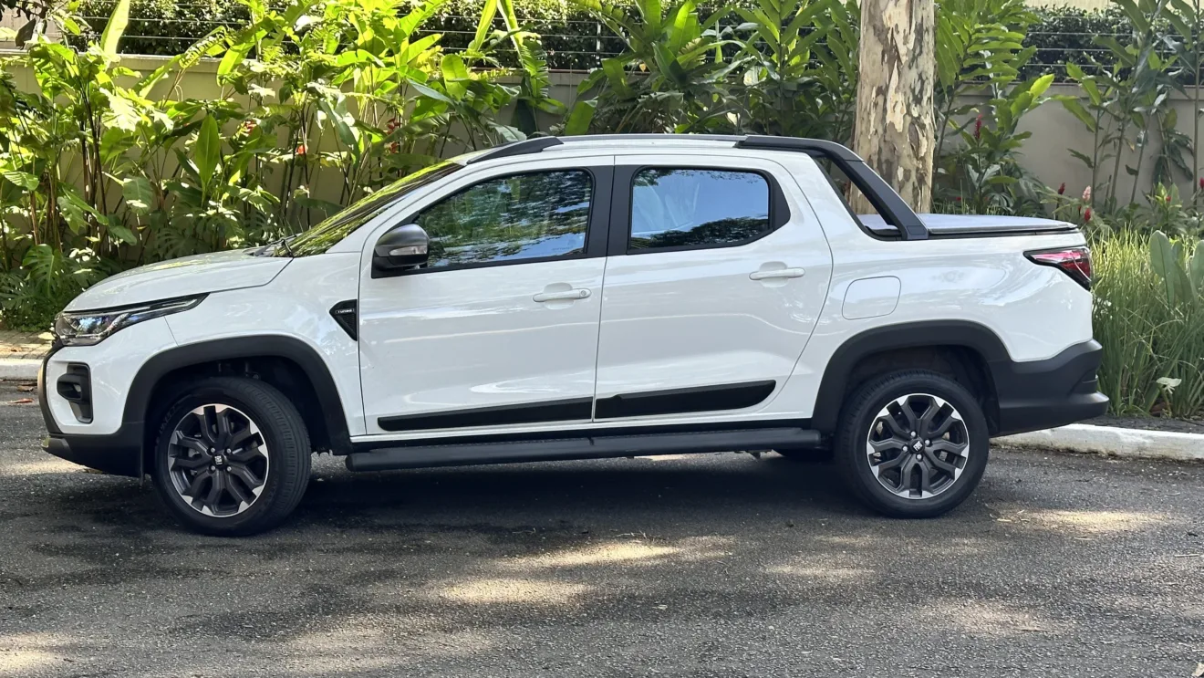 Fiat Strada Ultra branca, vista de lado e com mato ao fundo