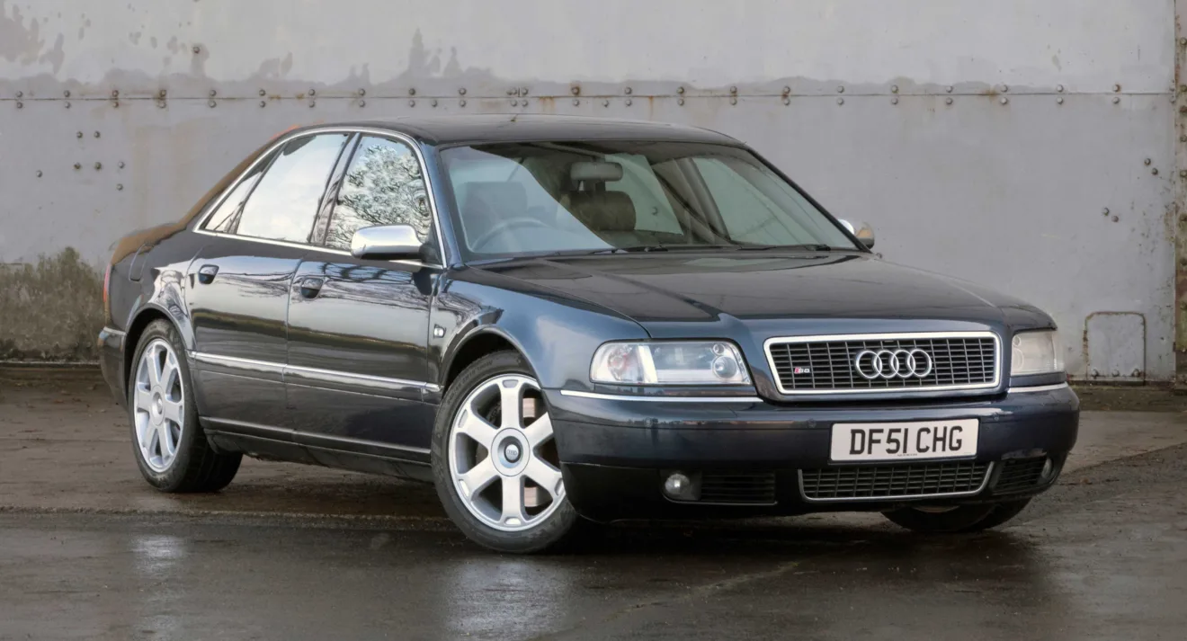 Audi S8 cinza parado de frente com muro ao fundo foi um dos carros que marcou a década de 1990