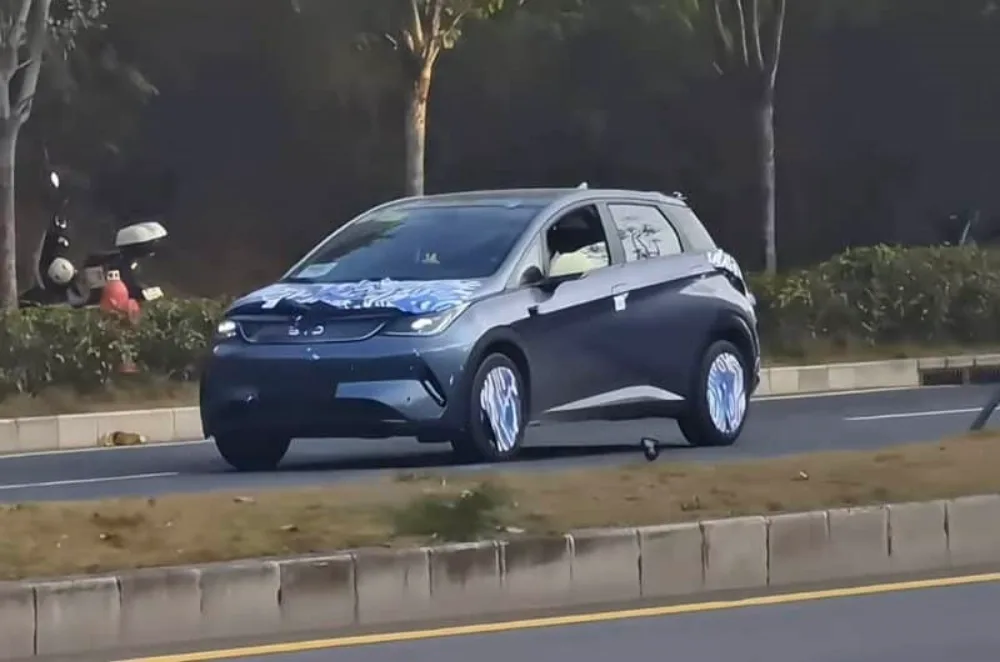 BYD Dolphin reestilizado azul, visto de frente, camuflado de azul e branco e com faróis acesos