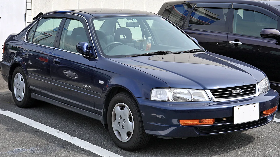 Isuzu Gemini azul de frente em um estacionamento 