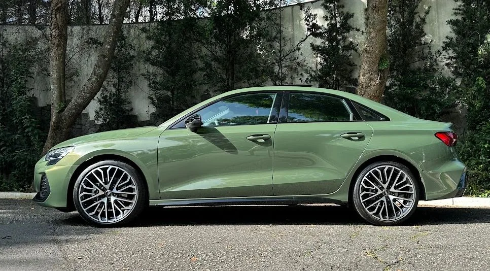 Audi A3 Sedan 2025 verde parado de lateral com árvores ao fundo