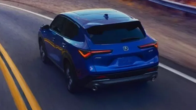Acura ADX azul, visto de trás, andando em uma estrada e com lanternas acesas