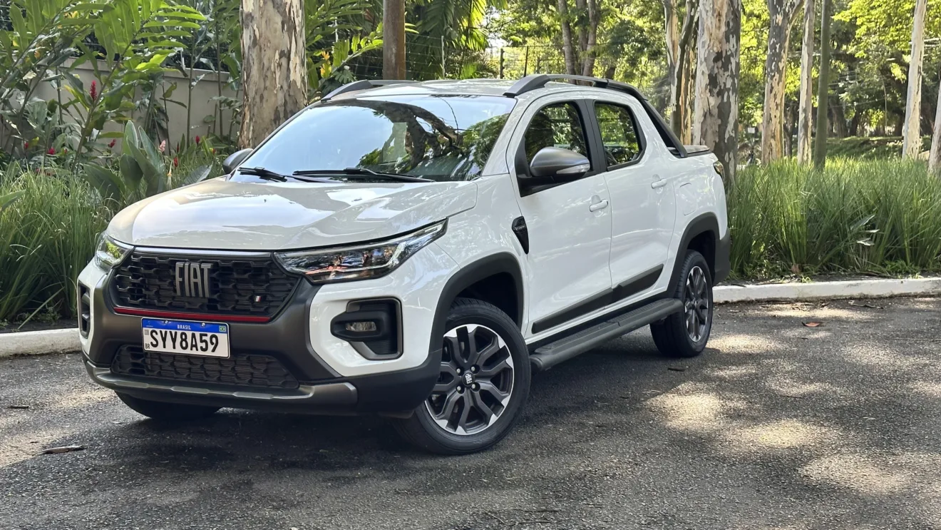 Fiat Strada Ultra branca, vista de frente e com mato ao fundo