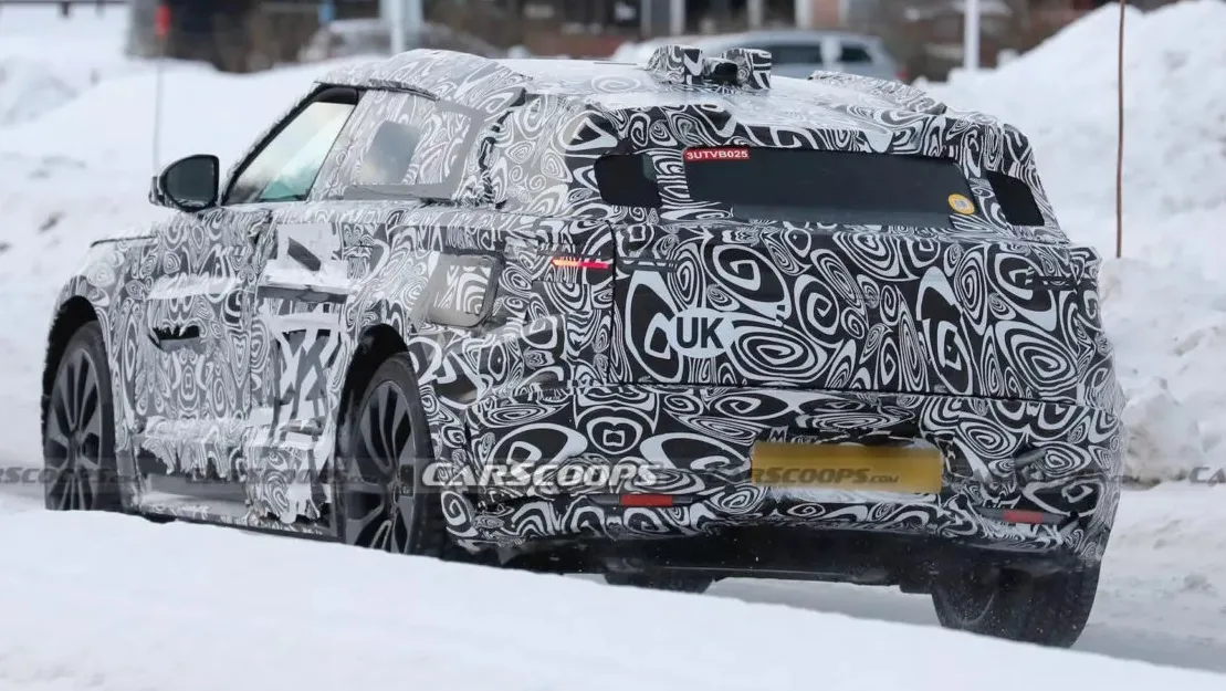 Protótipo do Land Rover Range Rover Velar elétrico camuflado de preto e branco, visto de trás, com lanternas acesas e neve ao fundo