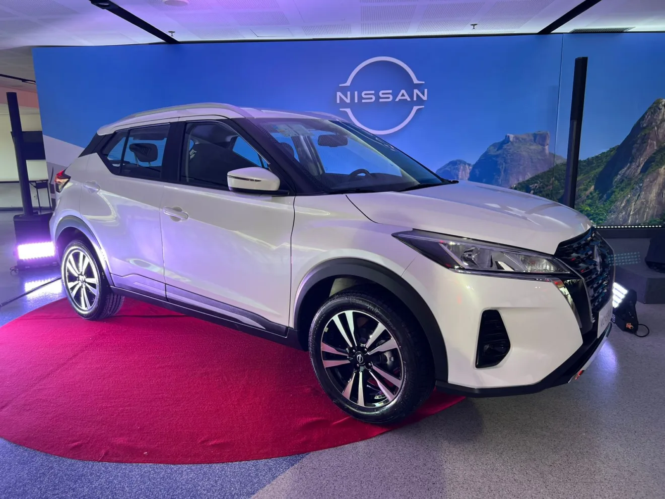 Novo Nissan Kicks Play 2025 branco com partes pretas, visto lateralmente e com fundo claro