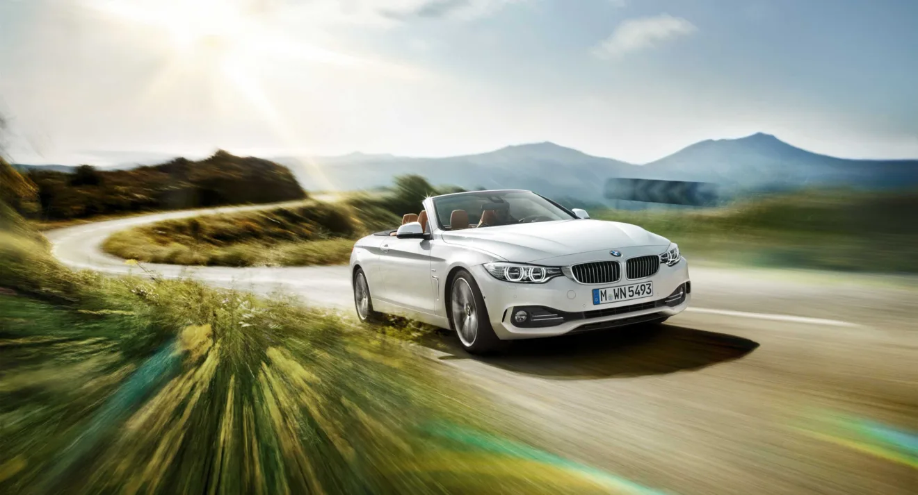 O carro BMW 428i Cabriolet Sport GP branco de frente em movimento na estrada