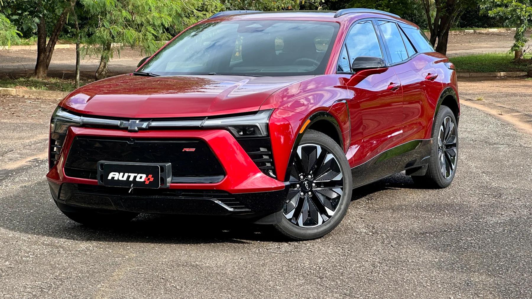 Chevrolet Blazer EV vermelho de frente em um estacionamento com árvores ao fundo