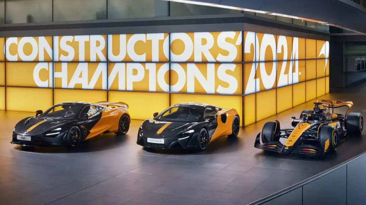 Modelos especiais MCL38 da McLaren, pintados de preto e laranja e vistos de frente com letreiro ao fundo