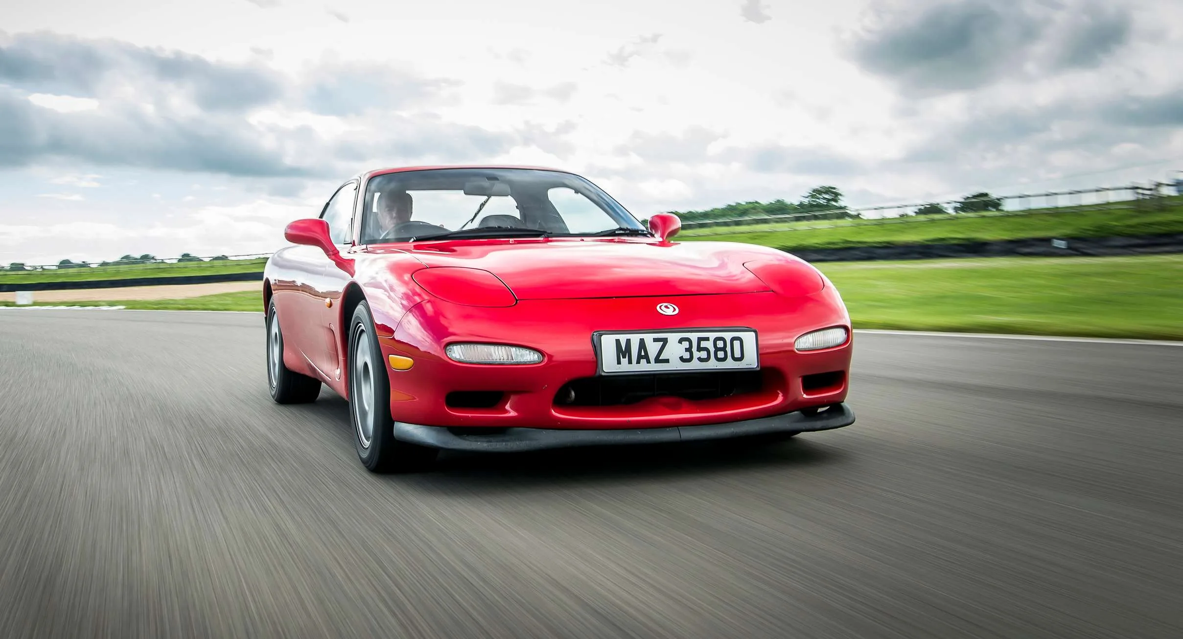 Mazda RX-7 vermelho de dianteira andando na pista