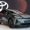 Toyota C-HR+ verde parado de frente com logotipo do fabricante ao fundo