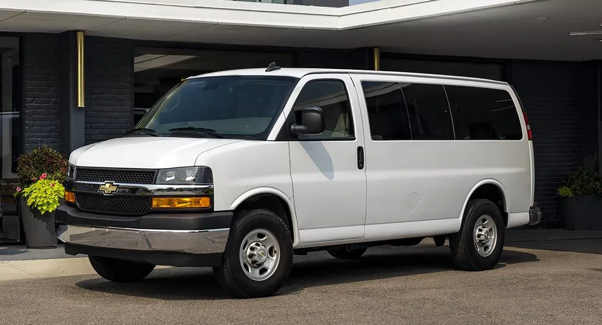 Van Chevrolet Express branca parada de frente com hotel ao fundo