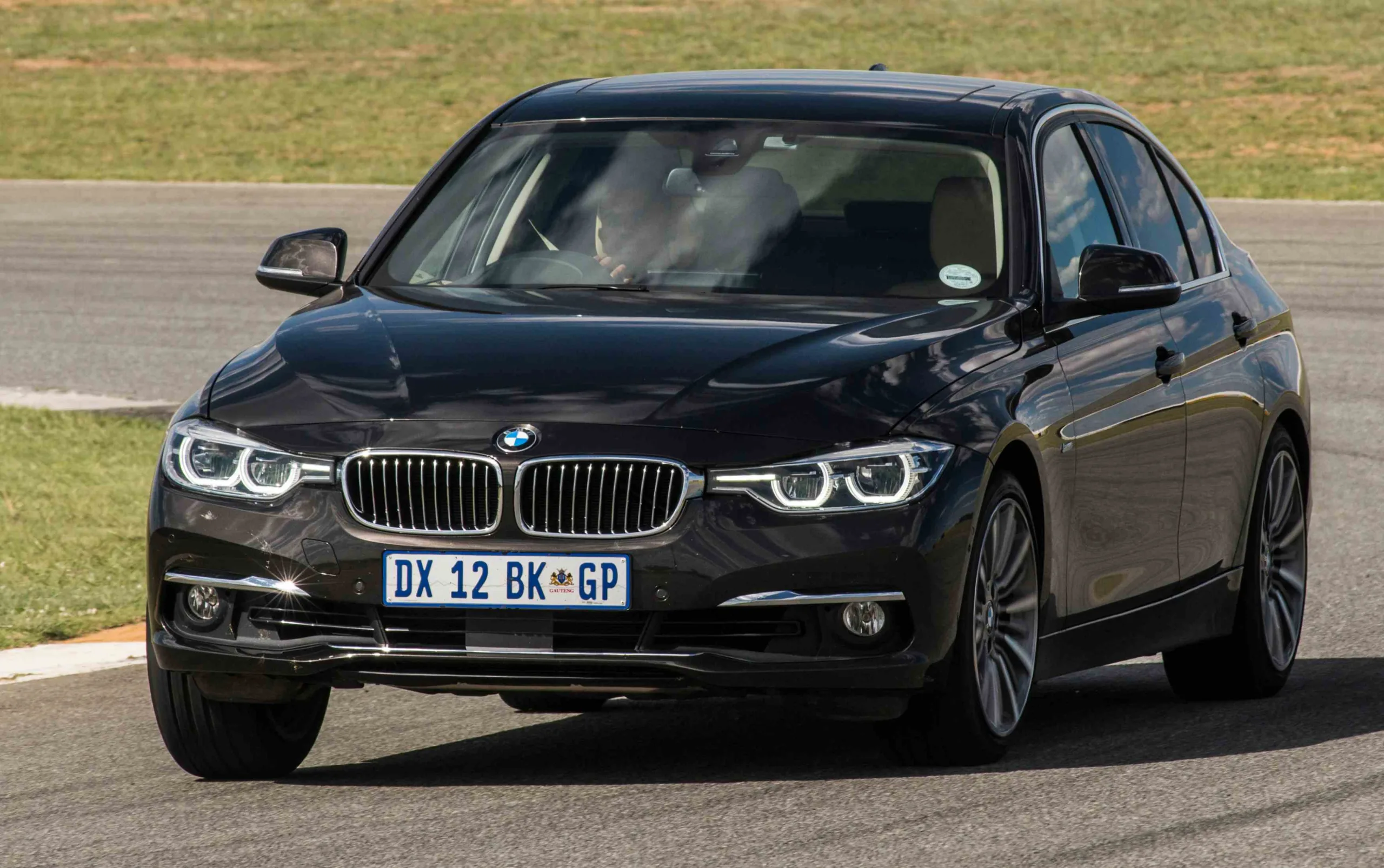 BMW 320i preta andando na pista é um carro que pode ser usado em Track Day