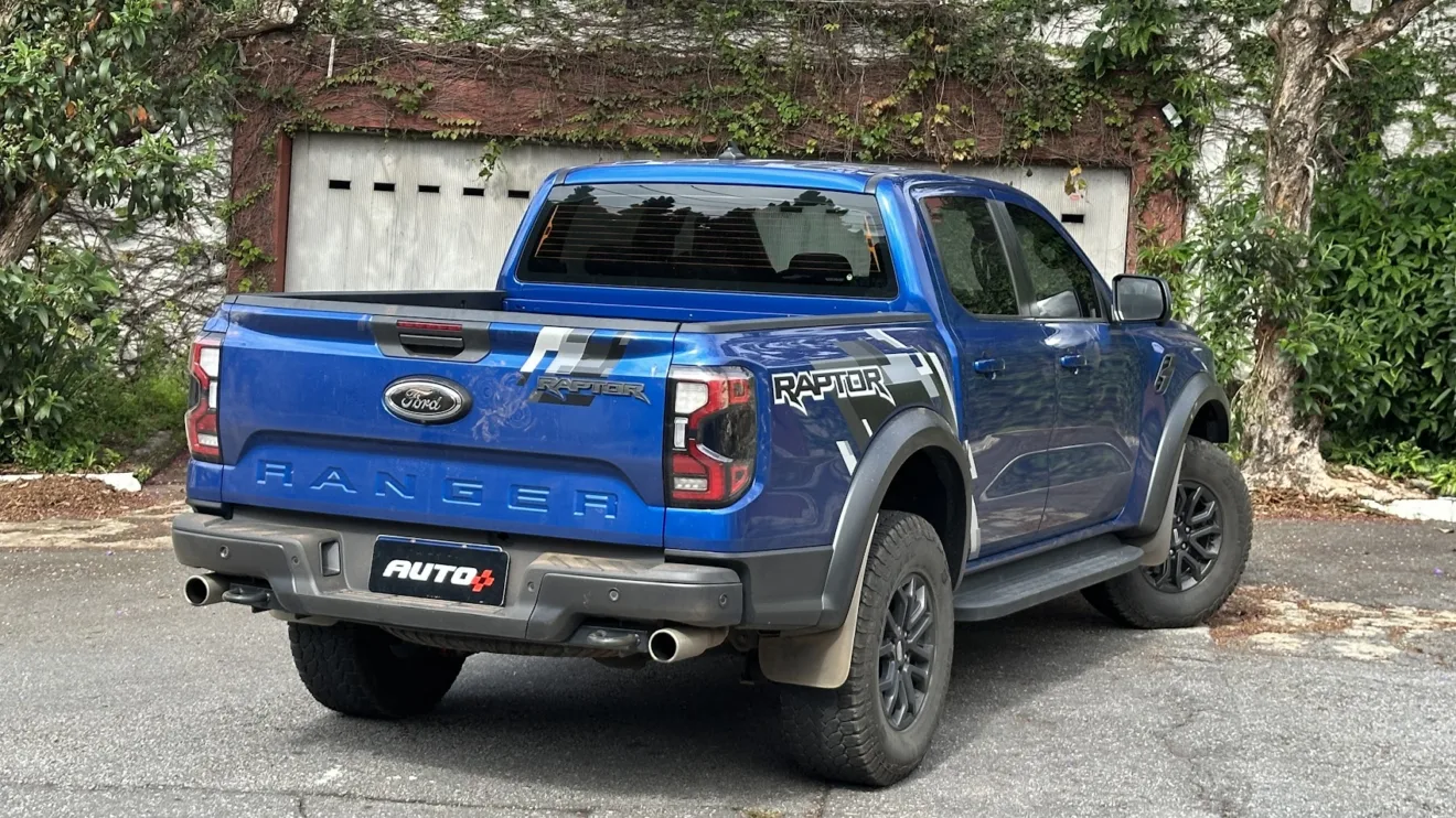 Ford Ranger Raptor azul parada de traseira com portão branco ao fundo