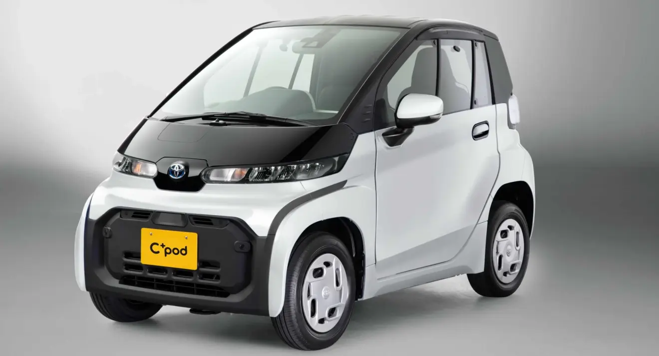 Toyota C+Pod branco e preto parado de frente com fundo cinza parece um carro de brinquedo