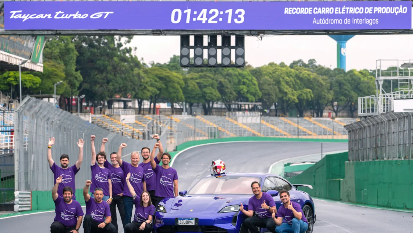 Equipe de corrida posando ao lado do Porsche Taycan Turbo GT com Pacote Weissach roxo ao centro