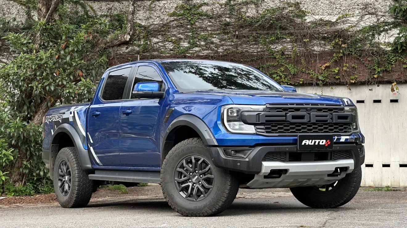 Ford Ranger Raptor azul parada de frente com portão branco ao fundo