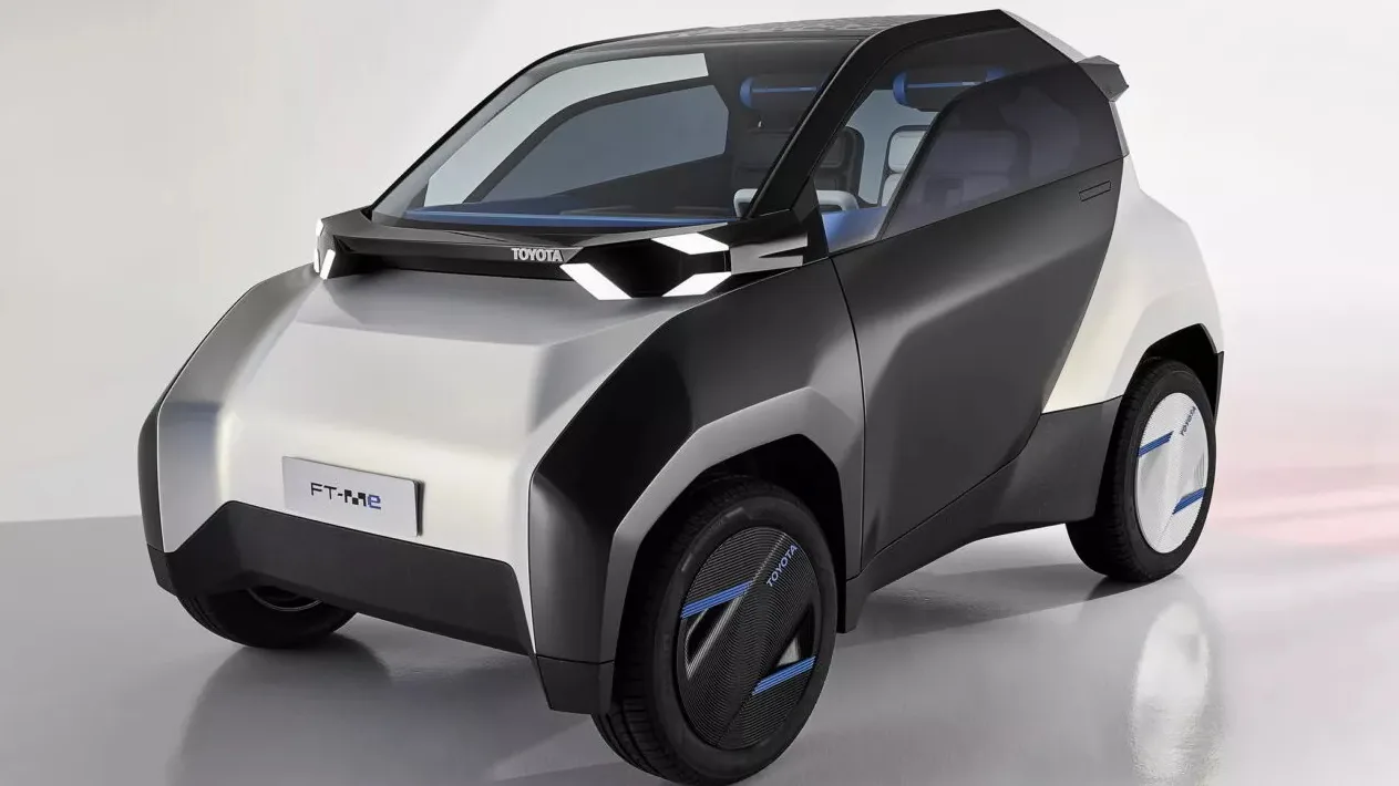 Toyota FT-Me Concept prata com partes pretas, visto de frente e com faróis acesos